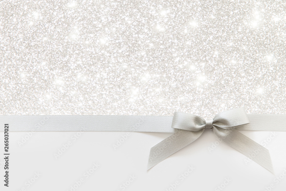 Silver ribbon with a bow as a gift on a white and Shiny background