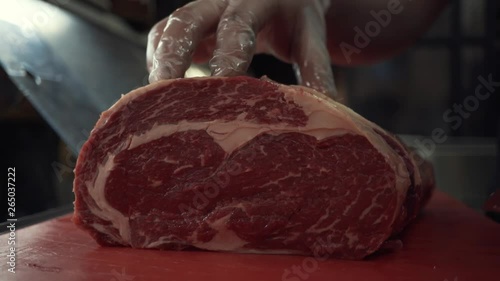 Close-up of somebody's hands in protective gloves neatly chopping the meat on the cutting board. Action. Cutting meat photo