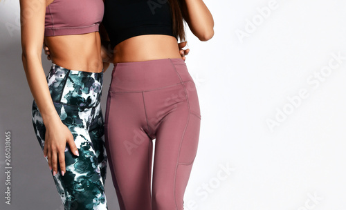 Two girls in athletic body cloth sport wear pants on gray photo