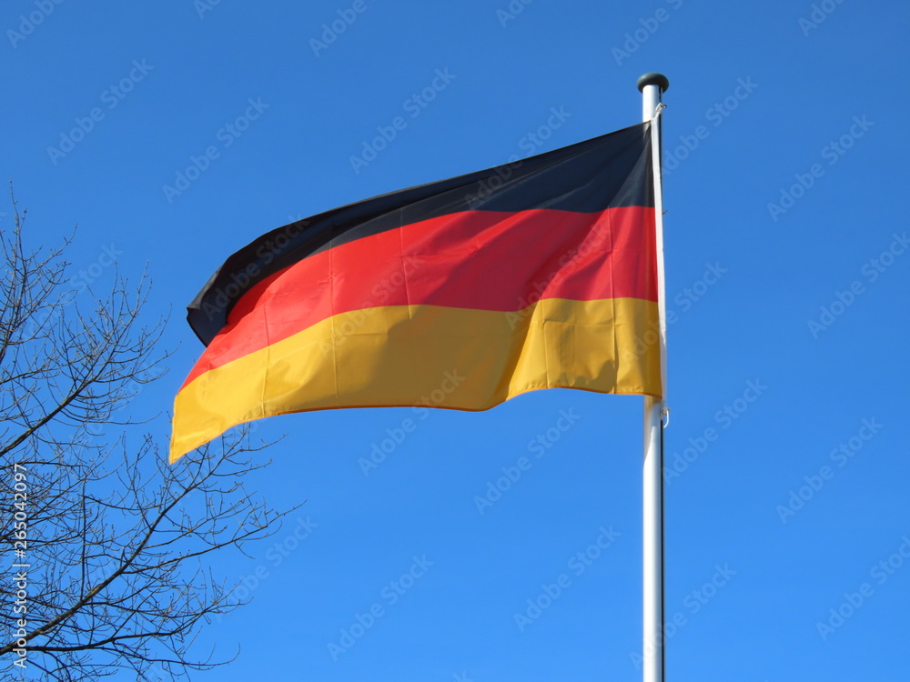 Germany flag bold and proud floating in the wind, against sunny blue sky Germany flag bold and proud floating in the wind, against sunny blue sky