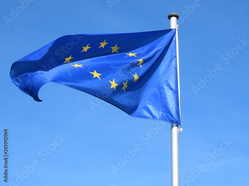 European Union flag bold and proud floating in the wind, against sunny blue sky