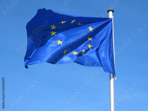 European Union flag bold and proud floating in the wind, against sunny blue sky