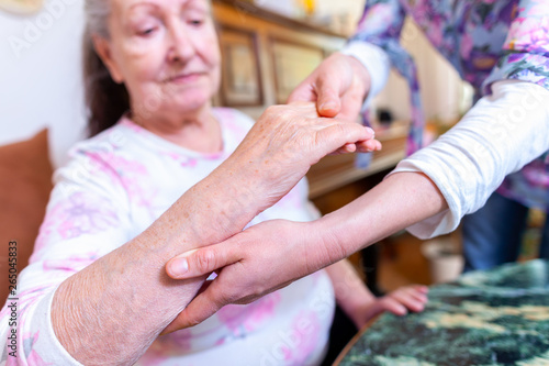 A young woman is holding the hand of an old woman photo