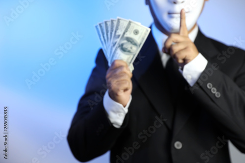blurred image of politician or businessman wearing black suit and white mask show banknotes as a promise of buying vote of the upcoming elections and do not tell to anyone photo