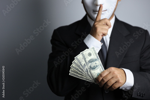 politician or businessman wearing black suit and white mask show banknotes as a promise of buying vote of the upcoming elections and do not tell to anyone photo