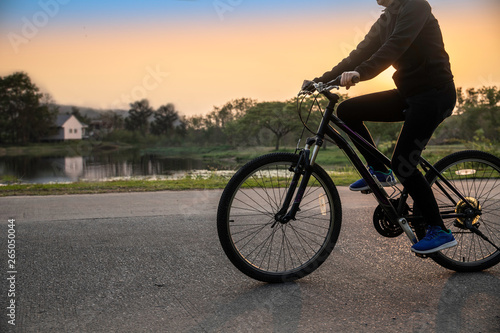 A middle woman active biking in the park at sunset background.