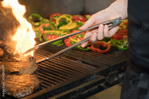 Flame kissed steaks on commercial grill with bell peppers