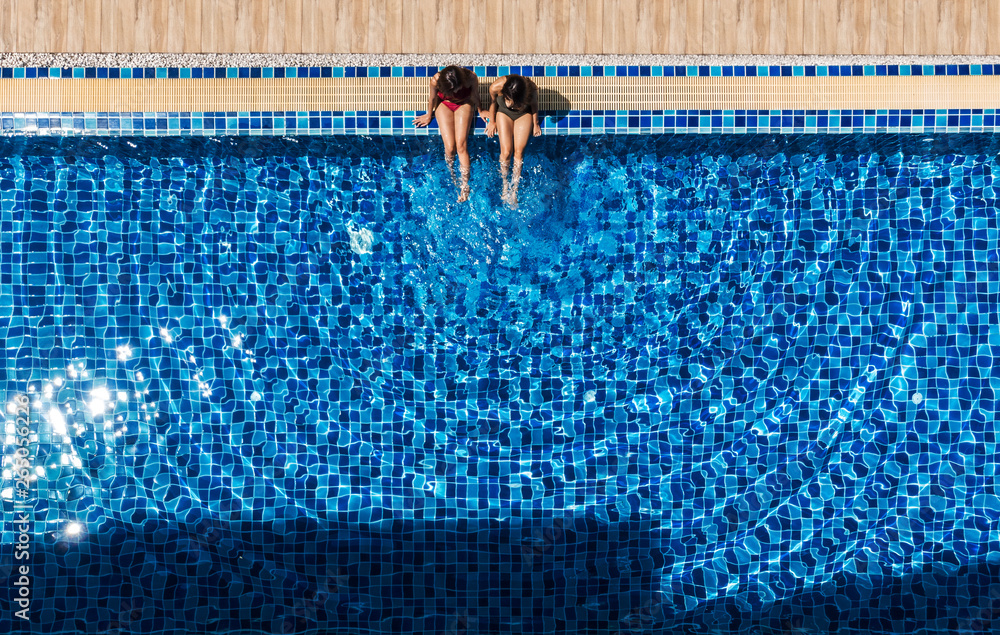 two women relaxing and sitting at swiming pool.