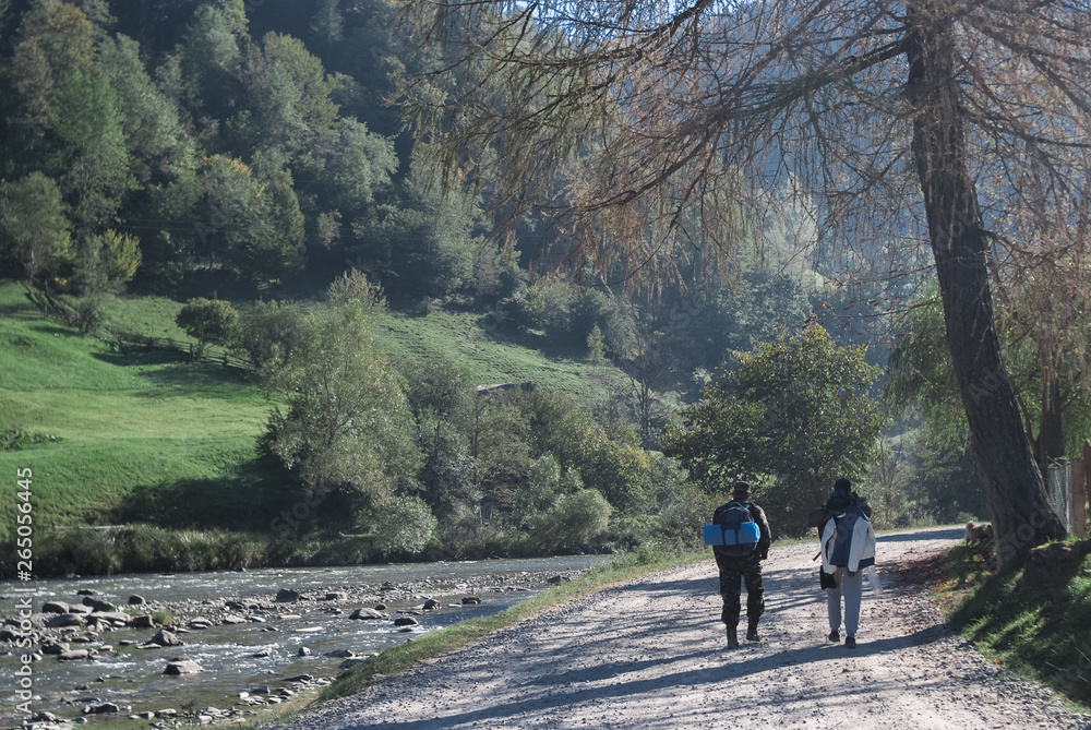 Two men walking near mountain river stream valley scenery landscape in summer day Two men walking near mountain river stream valley scenery landscape in summer day