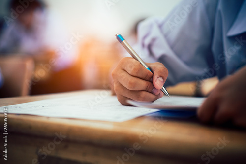 Hand of students writing and taking exam with stress in classroom photo