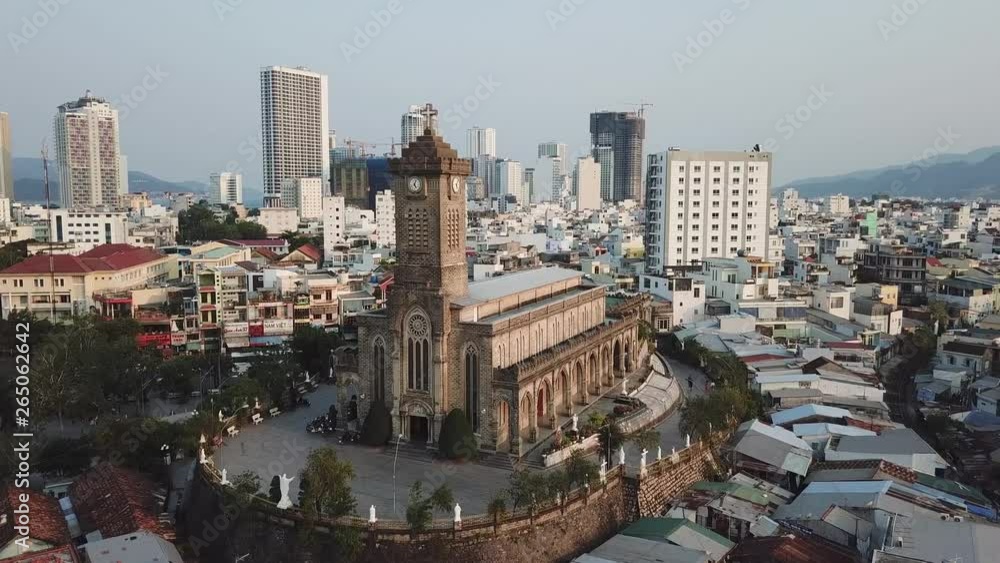 Aerial approach catholic cathedral Tho Nui Nha Trang Vietnam clock stone tower. Contrast cityscape slums modern skyscrapers. Beautiful old authentic architecture religion traditional. Sunset blue sky Aerial approach catholic cathedral Tho Nui Nha Trang Vietnam clock stone tower. Contrast cityscape slums modern skyscrapers. Beautiful old authentic architecture religion traditional. Sunset blue sky