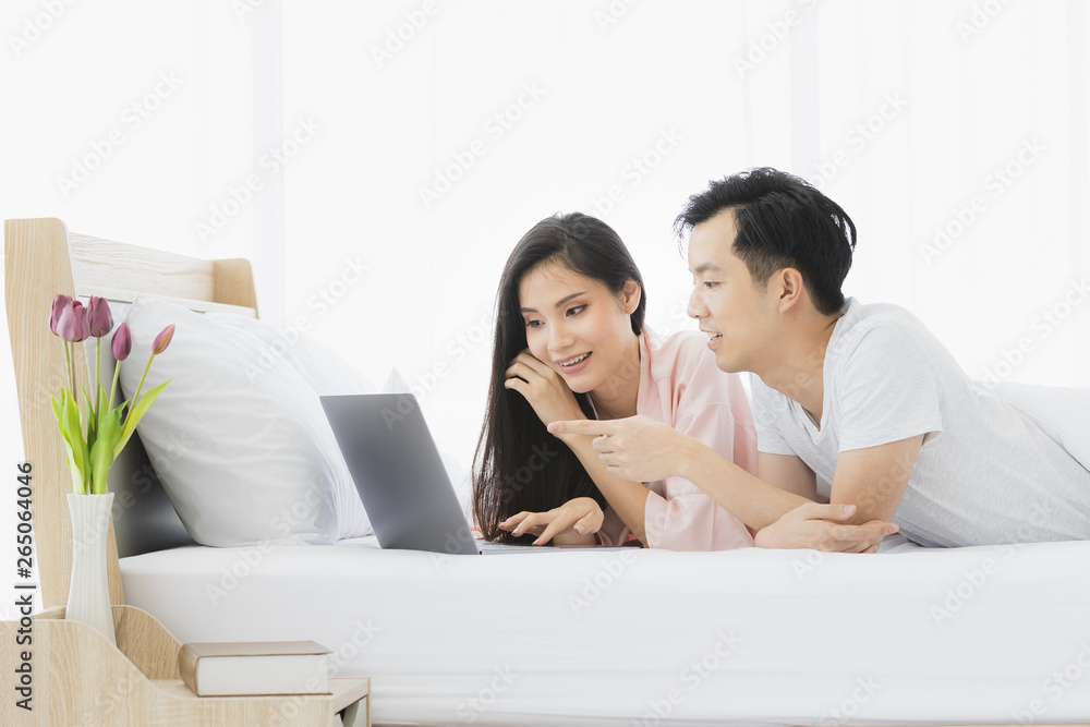 Asian couple lie prone on bed in bedroom. Asian couple lie prone on bed in bedroom.
