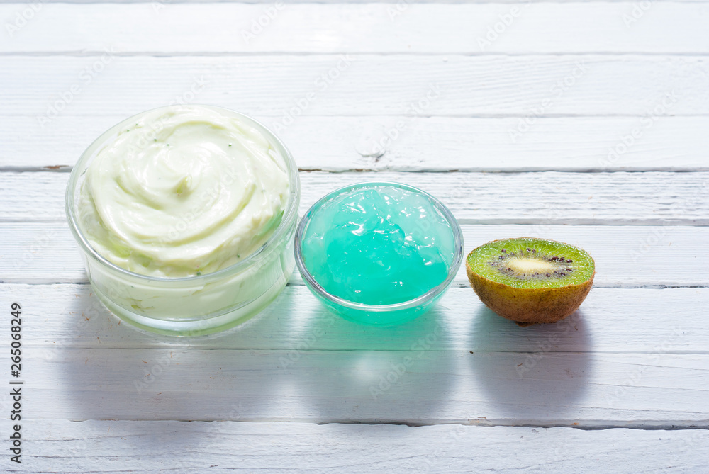 moisturizer and anti aging gel with kiwi on white wooden table moisturizer and anti aging gel with kiwi on white wooden table
