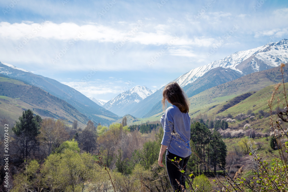 Naklejka premium Young girl on the background of spring mountains. Beautiful mountain gorge. Nature and adventure.