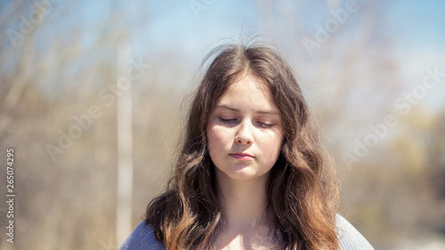 Young girl with positive emotions. Relaxed, pleased with a smile on her face. Spring natural background, forest and river.