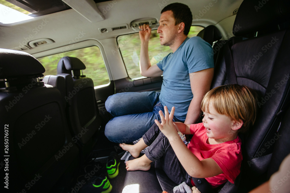 Fototapeta premium Boy and dad ride in the back seat of a car. Happy father and son sitting together in automobile
