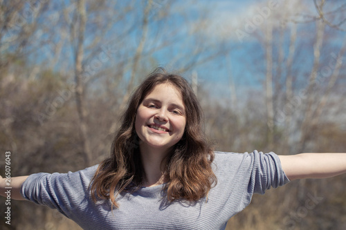 Young girl on nature with positive emotions. Relaxed, pleased with a smile on her face. Twists his head. Carefree fun pastime.