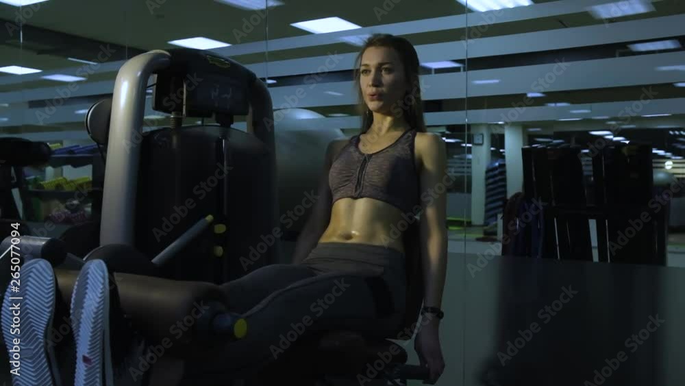 Beautiful girl engaged on a simulator in the gym on a black background Beautiful girl engaged on a simulator in the gym on a black background
