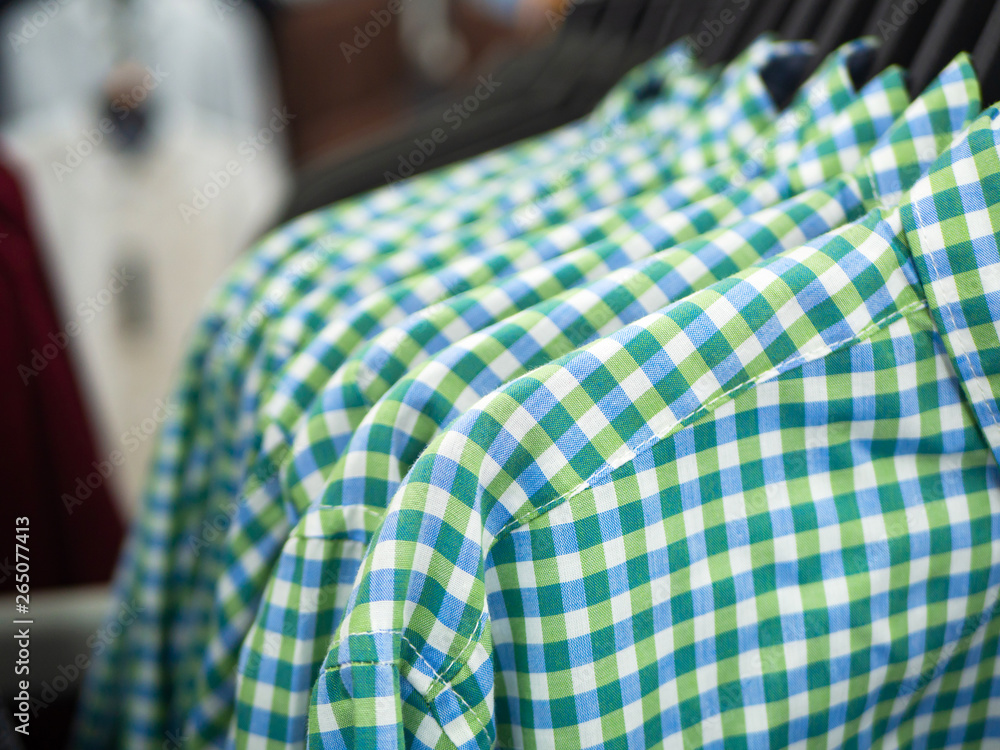 Close up of blue green plaid shirts on hangers in store Close up of blue green plaid shirts on hangers in store