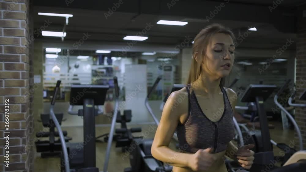 Beautiful girl engaged on a simulator in the gym on a black background Beautiful girl engaged on a simulator in the gym on a black background