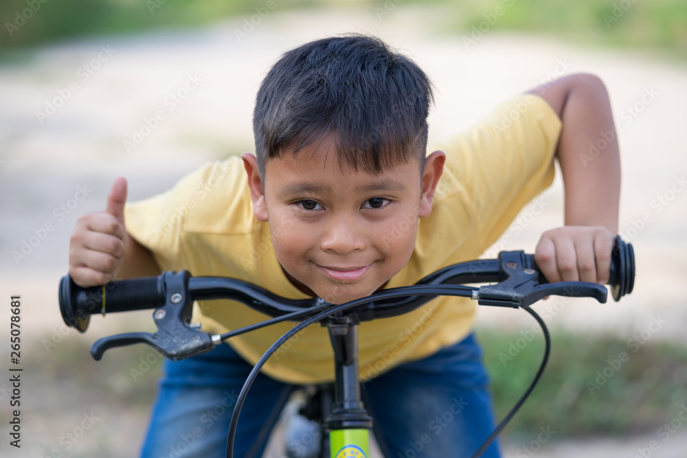 Obraz premium asian kid boy ride bicycle in nature
