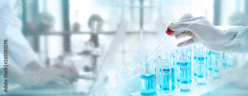 Test tubes with liquid in laboratory, Doctor hand holding dropper with dripping or transparent glass pipette, dropper for instillation. scientist working in laboratory. Banner for website advertising.