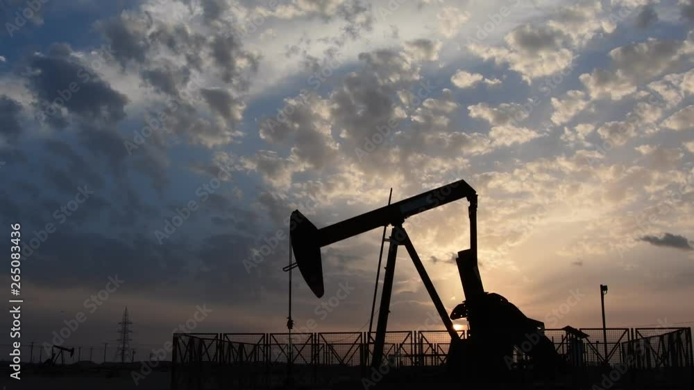 Silhouette of crude oil pump standing still in the oilfield at cloudy sunset Silhouette of crude oil pump standing still in the oilfield at cloudy sunset