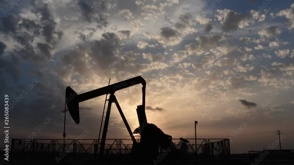 Silhouette of crude oil pump standing still in the oilfield at cloudy sunset Silhouette of crude oil pump standing still in the oilfield at cloudy sunset