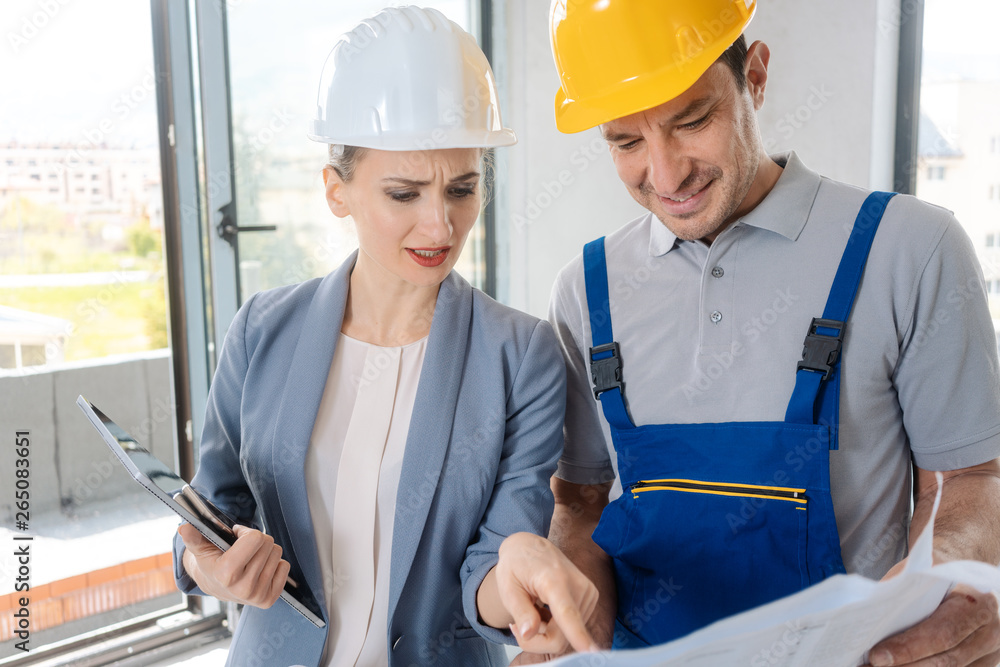 Construction worker and architect looking at plan on site