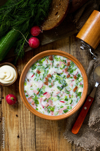 Delicious summer lunch. Spring-summer yoghurt cold soup  fresh vegetables and kefir on rustic wooden table. Copy space, top view flat lay background.