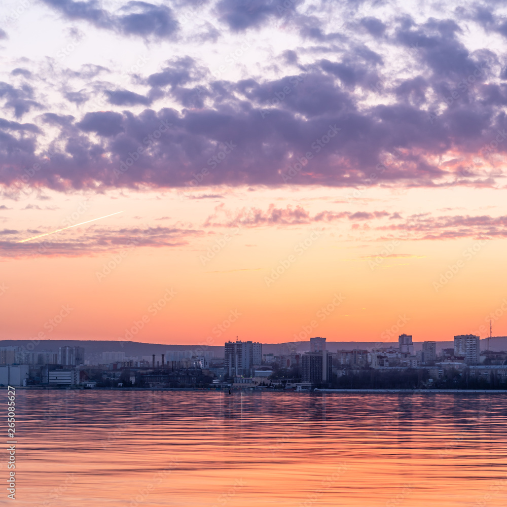 The city on the shore at sunset - a beautiful evening landscape, the city of Saratov on the banks of the Volga River.