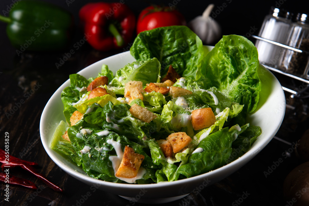 Fresh caesar salad on dark table