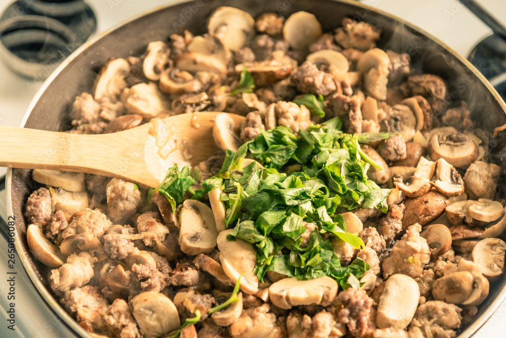 Cooking a stew of homemade sausages and mushrooms in a pan - traditional Italian mushroom sauce Boscaiola. Cooking a stew of homemade sausages and mushrooms in a pan - traditional Italian mushroom sauce Boscaiola.