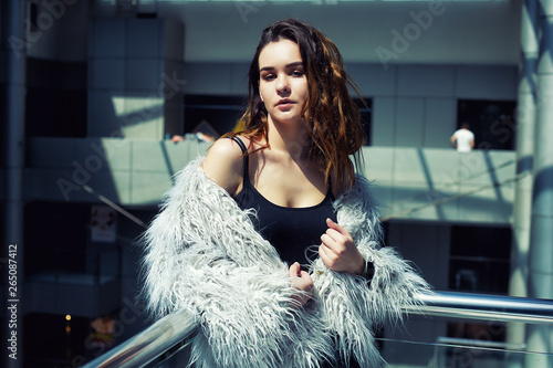 Portrait of a young fashionable woman in the city . The girl wears a dark t-shirt and a fur Cape