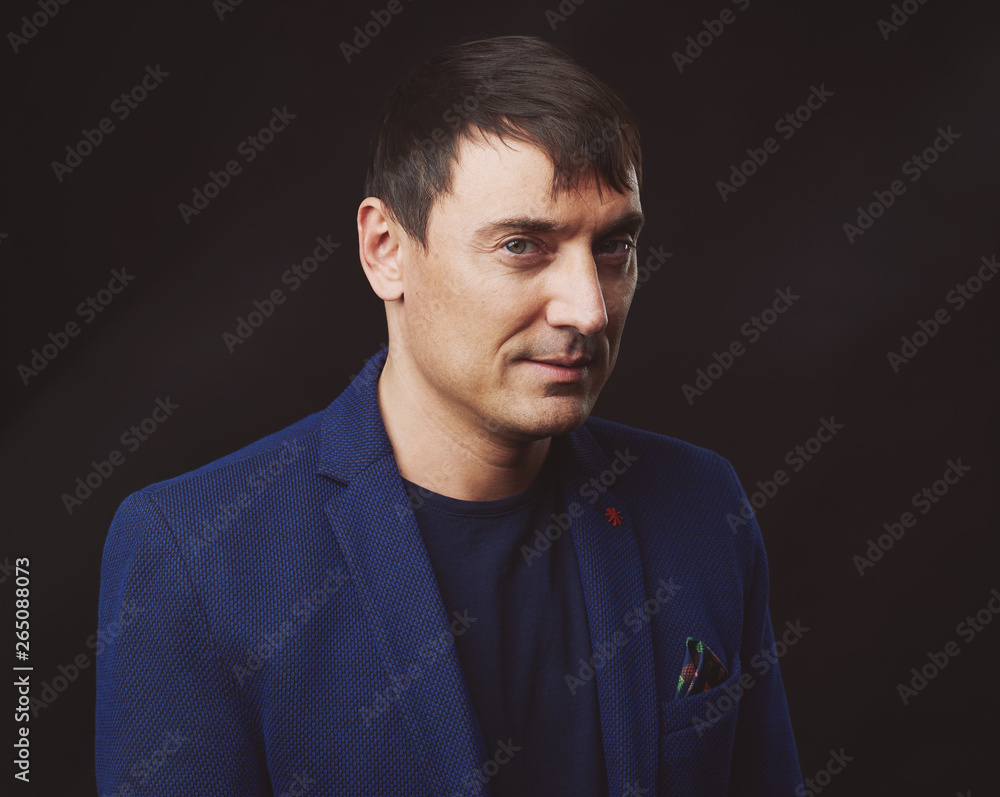 Portrait of handsome man wearing blue jacket, black background