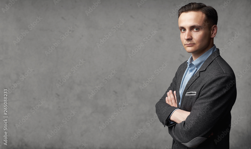 Portrait of young trendy man is standing before gray studio wall Portrait of young trendy man is standing before gray studio wall