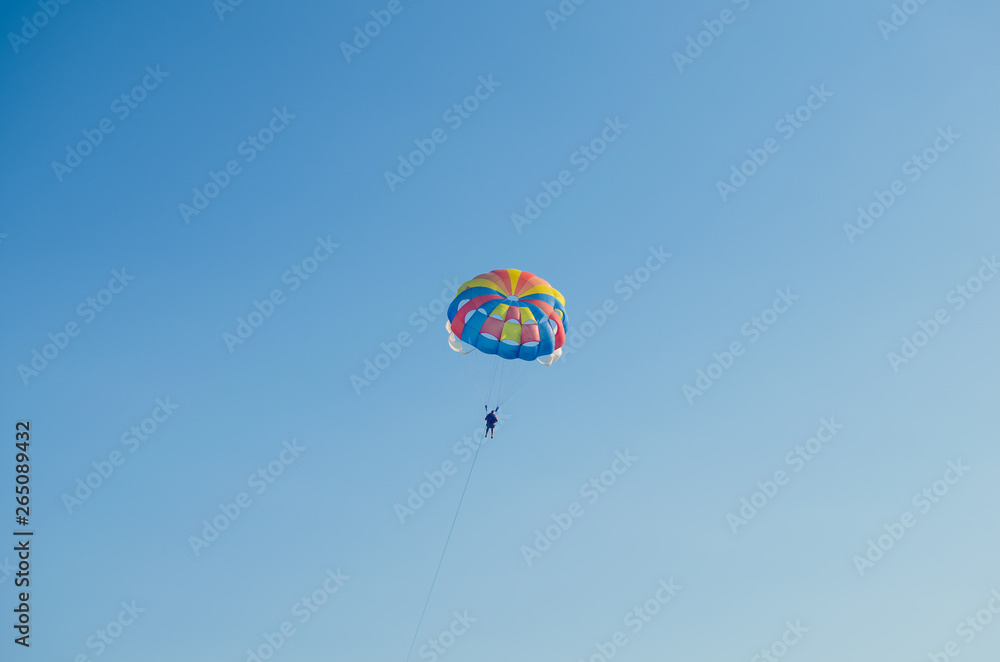 Fototapeta premium Parasailing is an extreme sport, people fly by parachute against the blue sky
