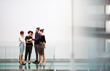 Group of young businesspeople standing near staircase, talking.