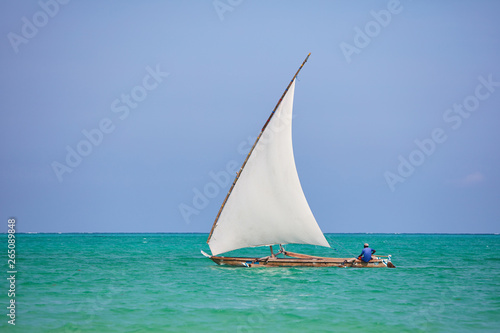 Sail boat with white sail and sitting sailor