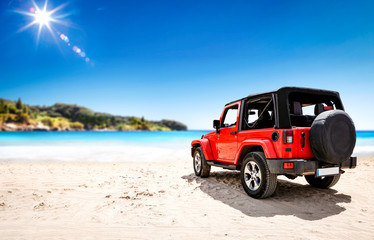 Red summer car on beach and free space for your decoration. Summer sunny day and blue sky. 
