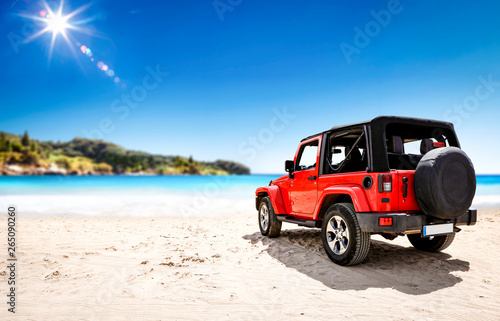 Red summer car on beach and free space for your decoration. Summer sunny day and blue sky. 