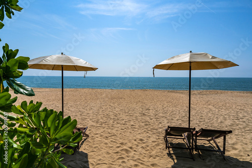 Tropical beach with sun umbrella under the palm trees in sunlight  vacation background