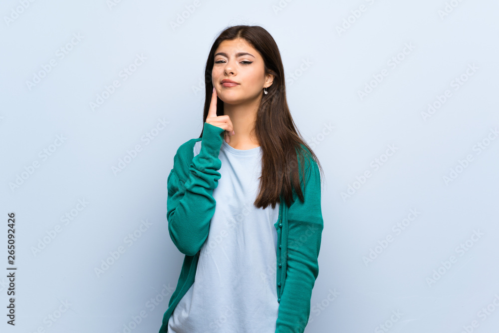 Teenager girl over blue wall Looking front Teenager girl over blue wall Looking front
