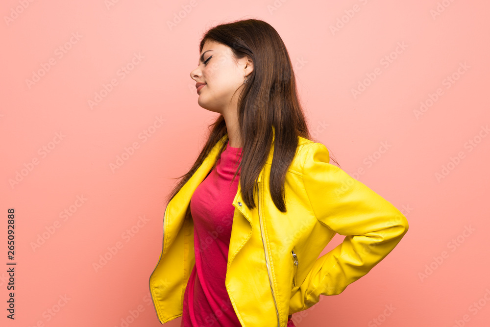 Teenager girl over pink wall suffering from backache for having made an effort Teenager girl over pink wall suffering from backache for having made an effort