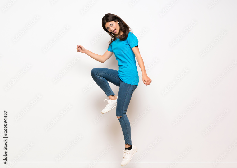 Teenager girl jumping over isolated white wall