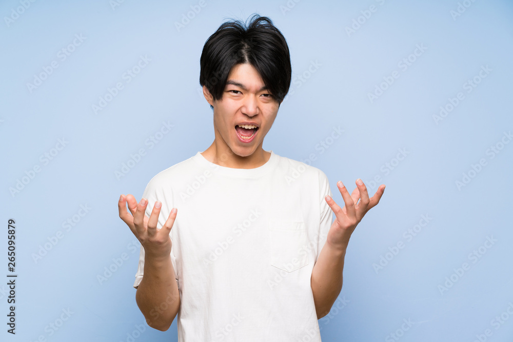 Asian man on isolated blue background unhappy and frustrated with something Asian man on isolated blue background unhappy and frustrated with something