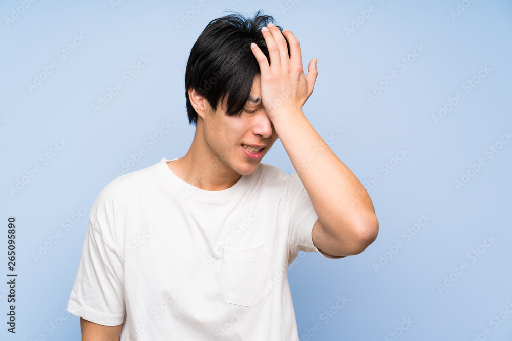 Asian man on isolated blue background having doubts with confuse face expression Asian man on isolated blue background having doubts with confuse face expression