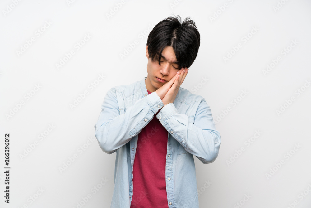 Asian man on isolated white background making sleep gesture in dorable expression Asian man on isolated white background making sleep gesture in dorable expression