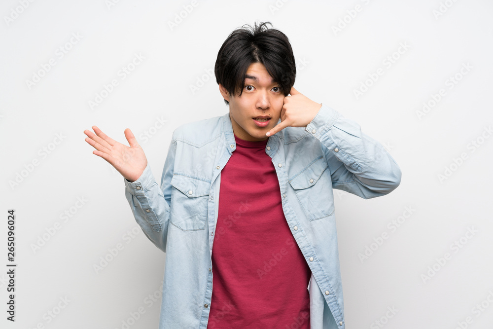 Asian man on isolated white background making phone gesture and doubting Asian man on isolated white background making phone gesture and doubting