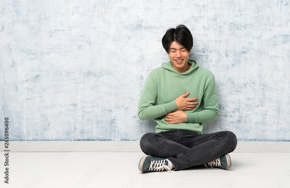 Asian man sitting on the floor smiling a lot Asian man sitting on the floor smiling a lot